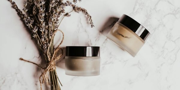 Skincare jars and lavender arranged on a marble surface, perfect for beauty and wellness themes.